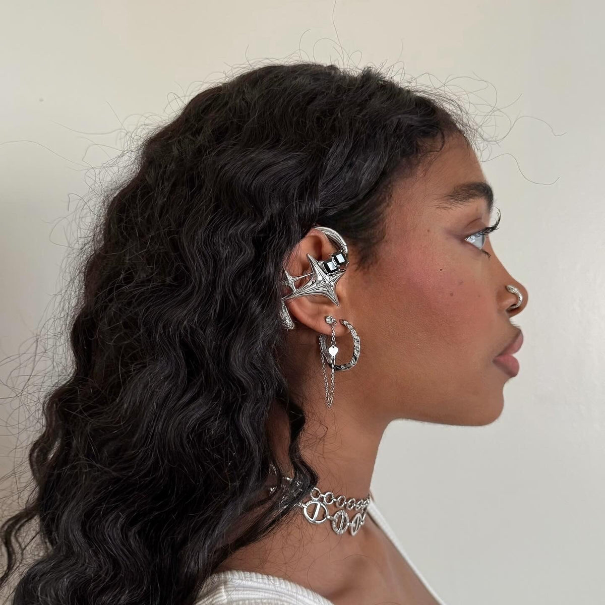 Silver-toned NEBULA ear-hook earphones shown in profile with a white top.