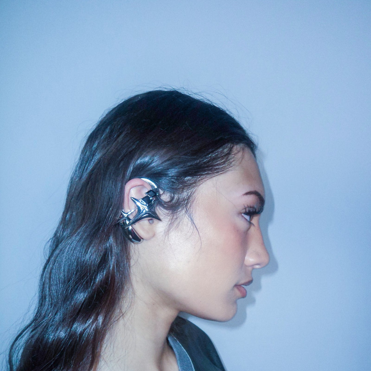 Side-profile portrait of NEBULA ear-hook earphones against a blue background.