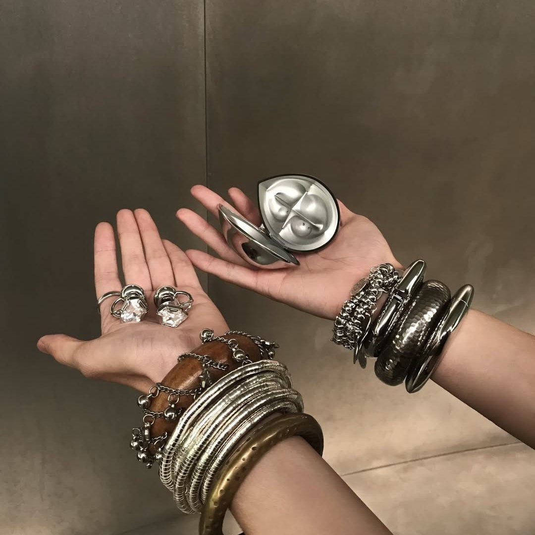 Electronic Gems earphones resting in one palm, with their open charging case in the other hand.