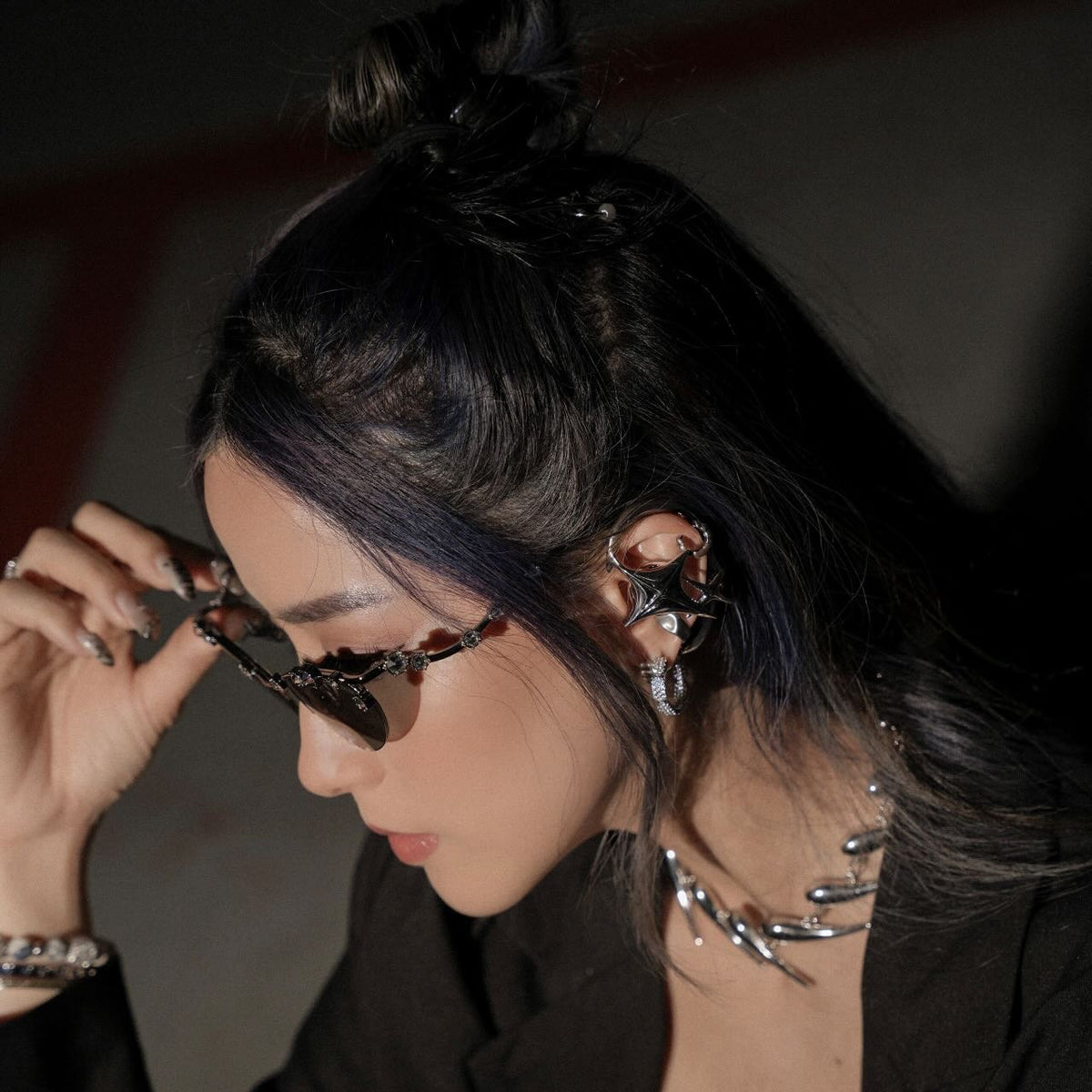 NEBULA ear-hook earphones styled with sunglasses and a black jacket.