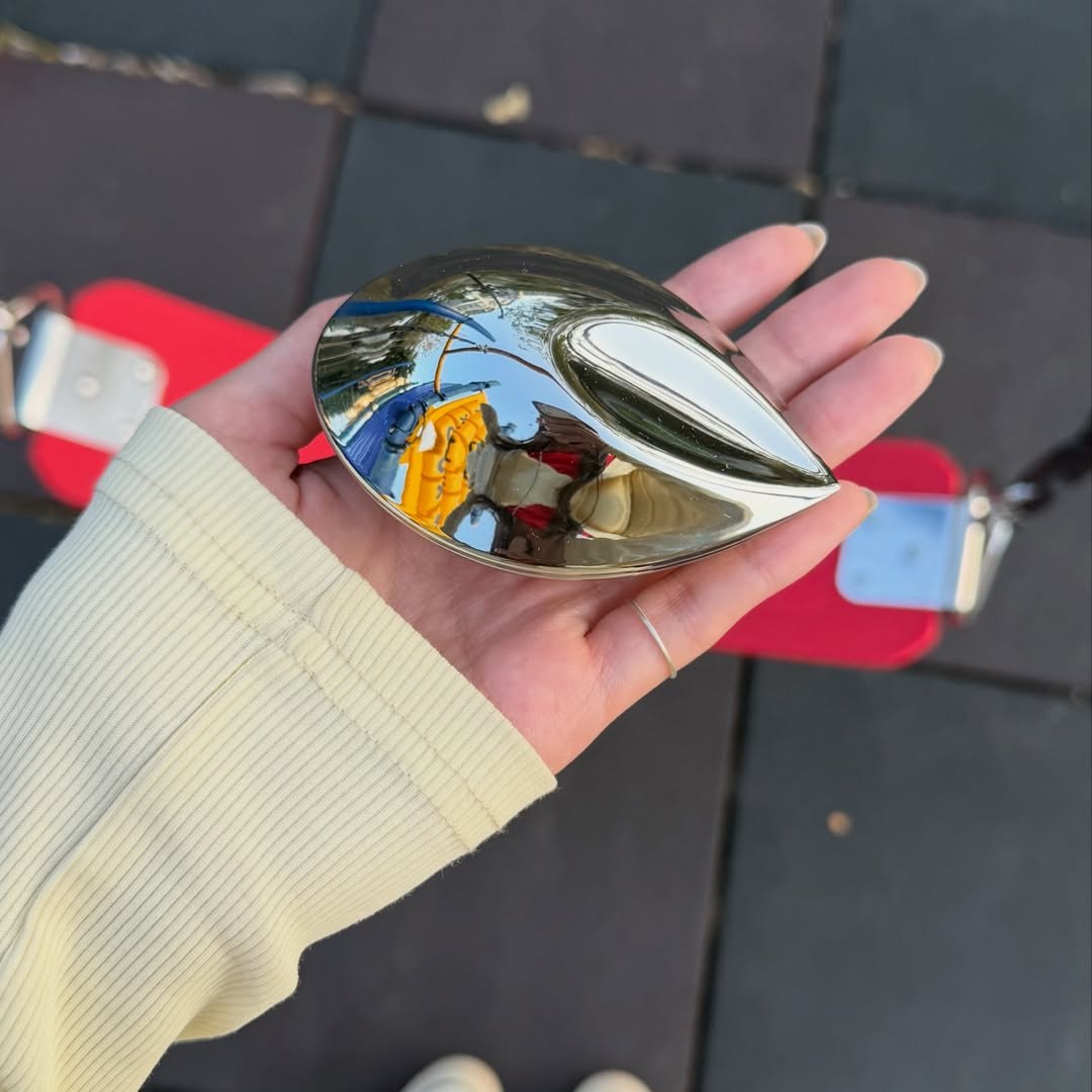 A closed Electronic Gems charging case resting in a hand outdoors.
