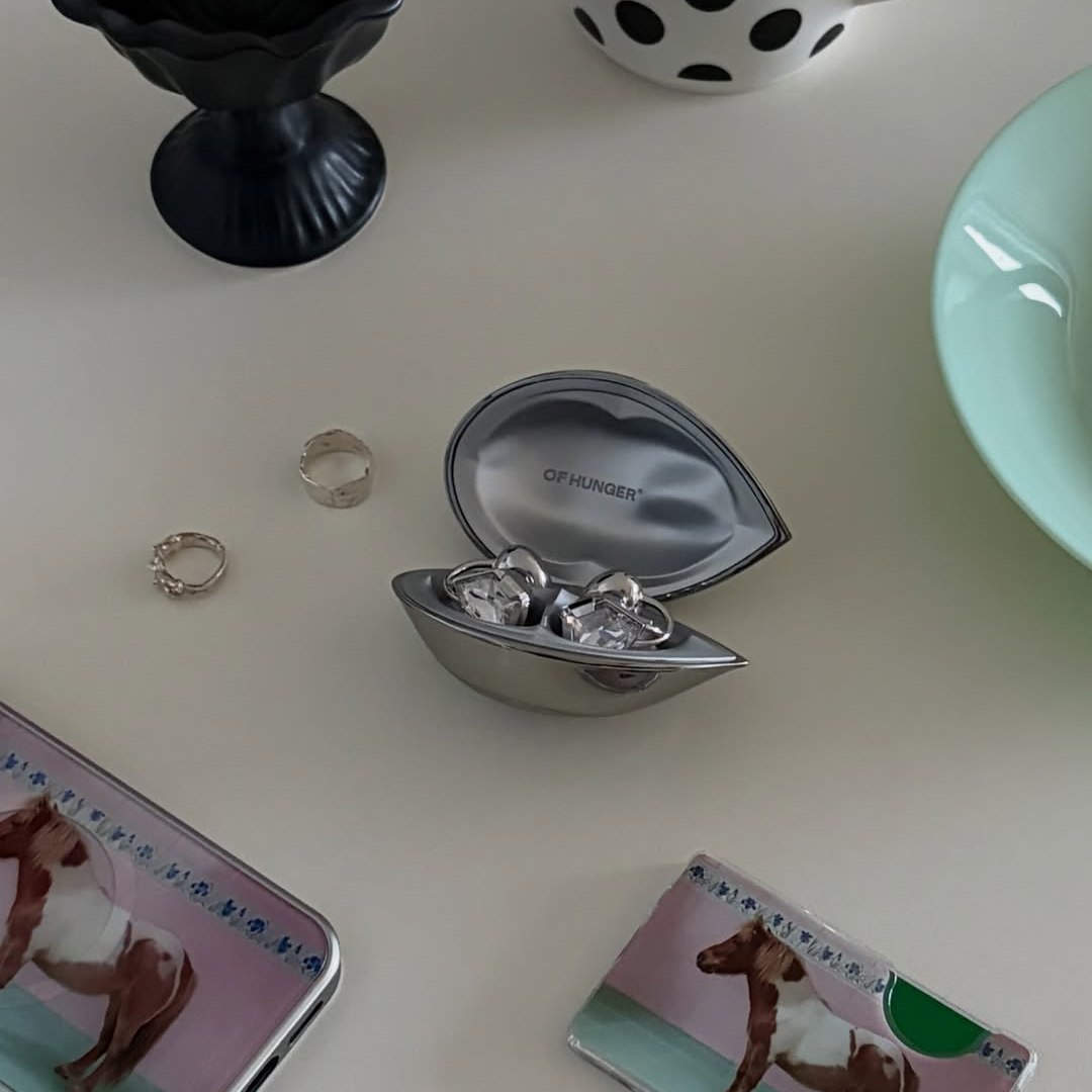 An open Electronic Gems case on a table beside rings and small photographs.