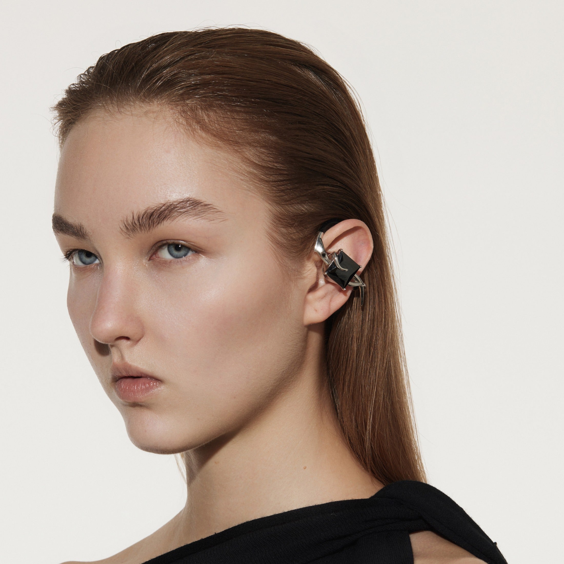 Model wearing OF HUNGER black gemstone ear cuff earphones with a black outfit