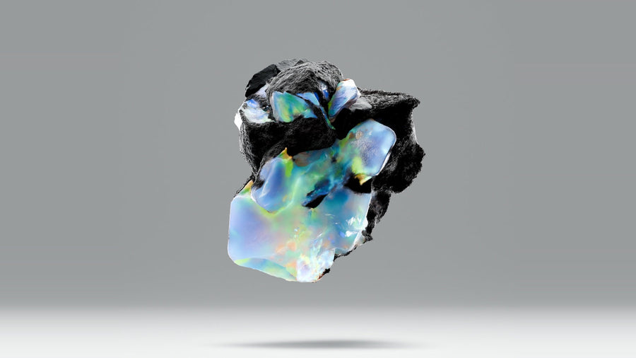 Iridescent opal stone with blue and green color play floating against a soft gray background