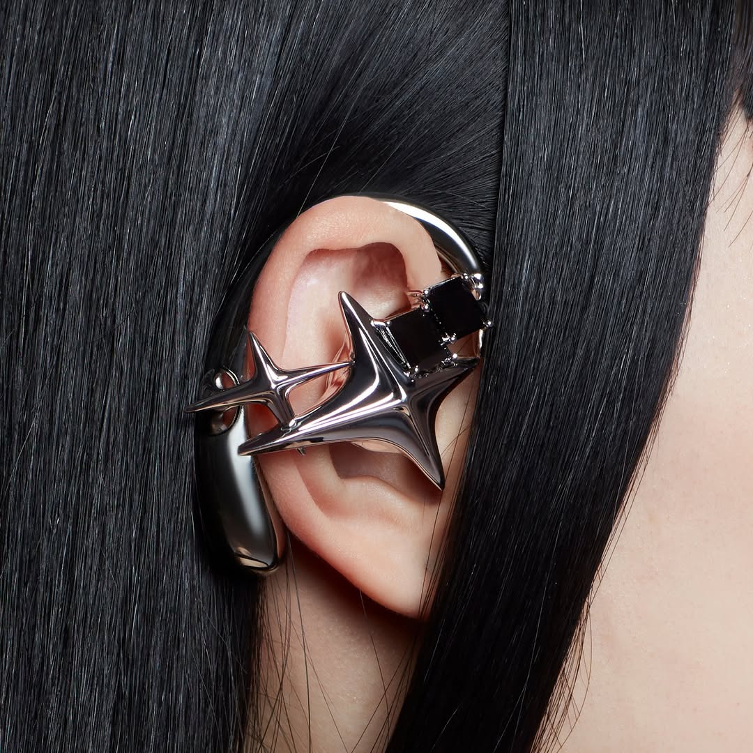 Silver star-shaped NEBULA accessory earphone worn against dark hair