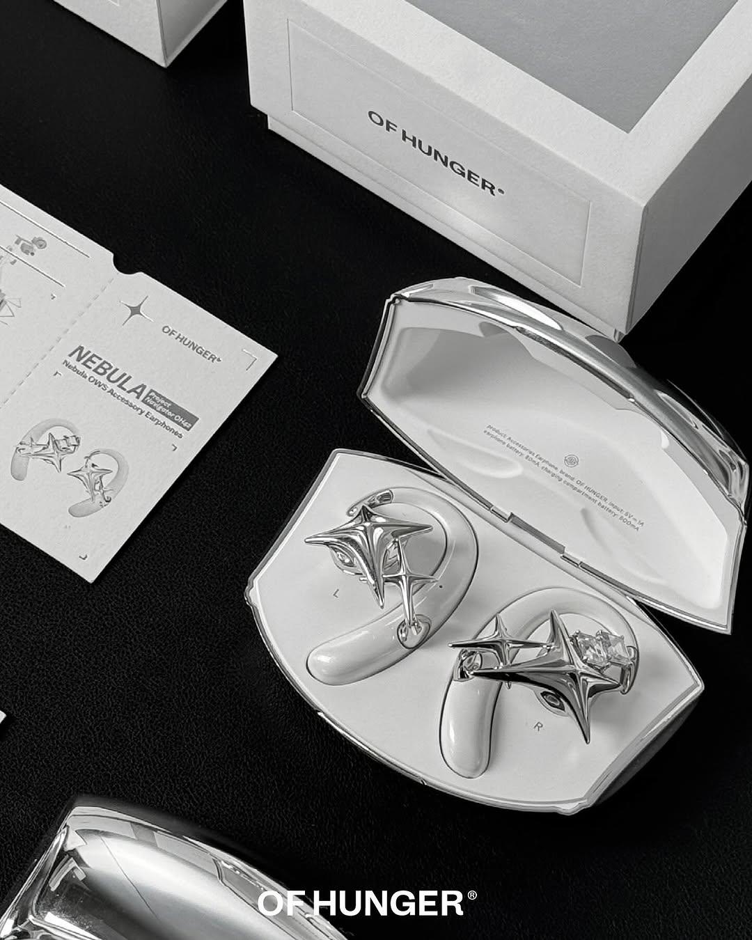 Silver NEBULA accessory earphones in an open metal case with printed cards