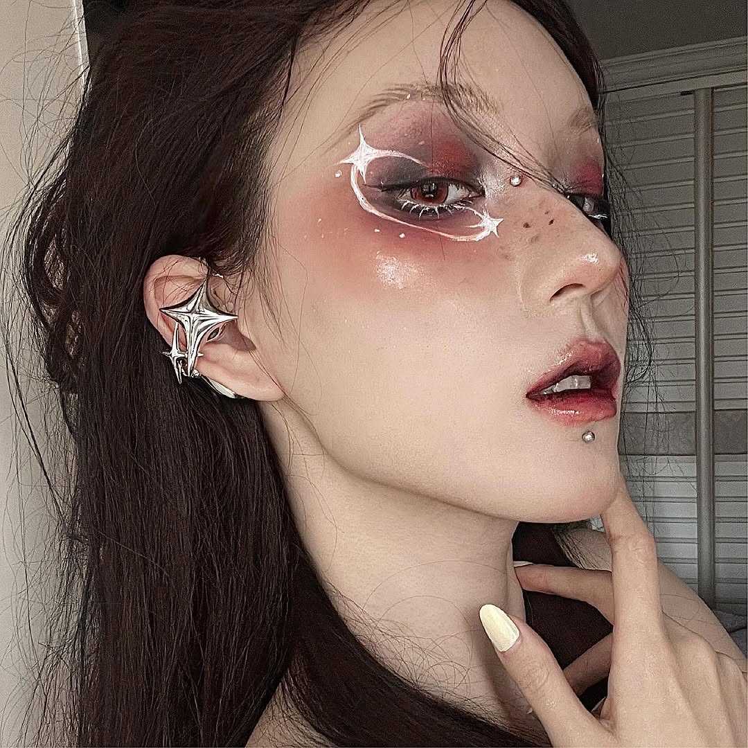 Model with red eye makeup, white star lines and a silver NEBULA ear form